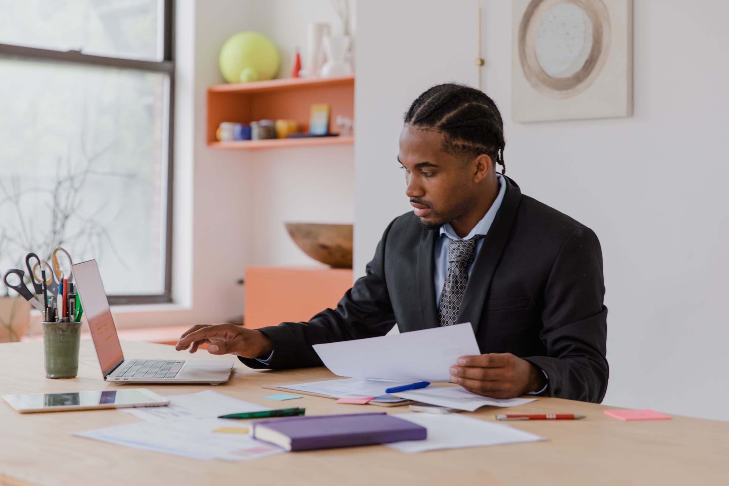 Business owner at a bright desk reading a printed website quote beside a laptop and paperwork